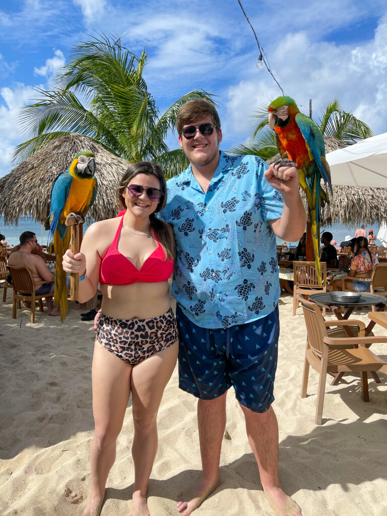 a couple in swimsuits each holding a parrot