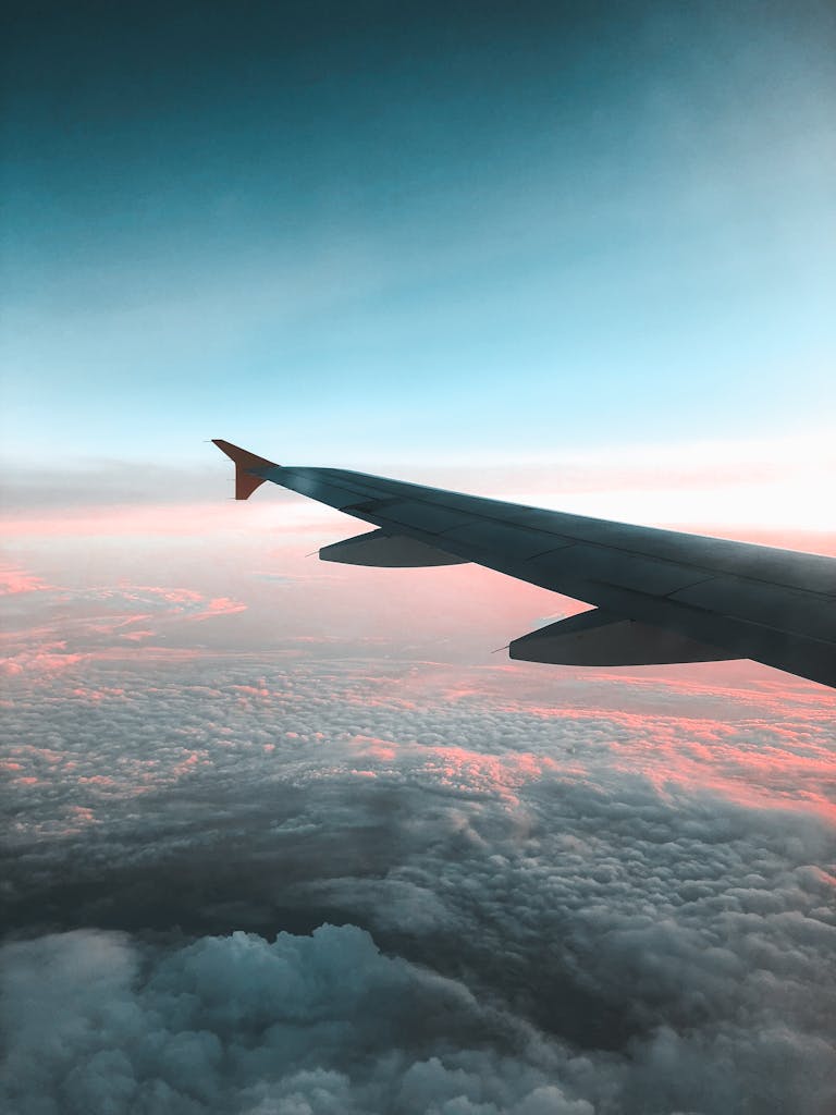 Dramatic view of an airplane wing over a colorful sunset cloudscape, capturing the essence of air travel.